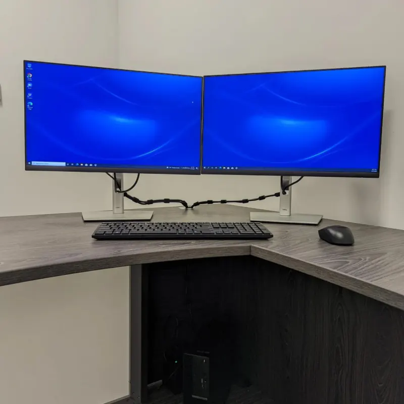 Dual-monitor workstation on a corner desk with the cabling tidied